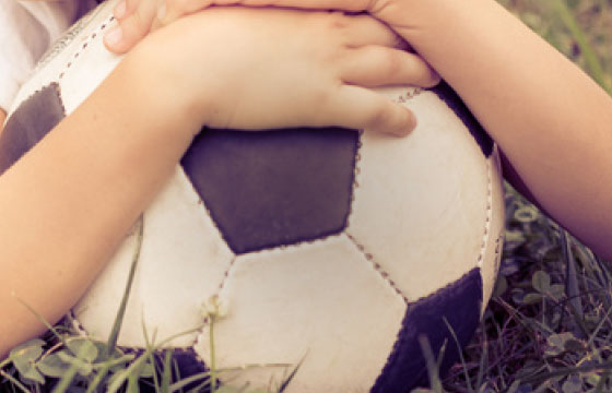Mehrere Kinderhände auf einem schwarz-weißen Fußball