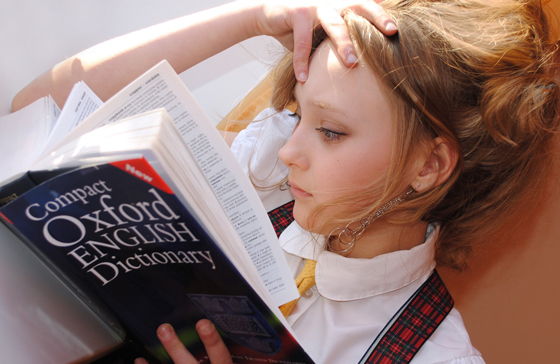Mädchen in Schuluniform liest das Oxford English Dictionary